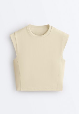 Top bej fără mâneci, scurtat, cu decolteu rotund și umeri structurați, așezat pe o suprafață albă.