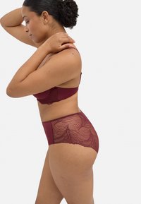 Conjunto de lencería burdeos con detalles de encaje en las bragas de cintura alta y el sujetador, con un acabado suave y bordes ondulados.