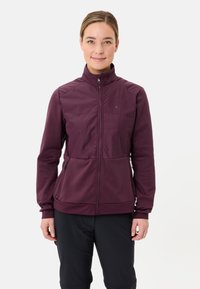 Giacca bordeaux con zip, colletto alto, pannello anteriore testurizzato e tasche laterali. Presenta un design aderente e polsini elasticizzati.