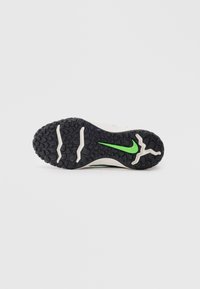 Črna podplata čevlja z teksturiranim oprijemom, dvema belima utoroma in zelenim logotipom Nike swoosh na sredini.