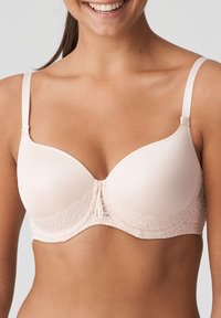 Reggiseno rosa chiaro con coppe lisce, bordi in pizzo e spalline regolabili. Presenta un dettaglio centrale con piccoli fiocchi per un tocco di design aggiuntivo.