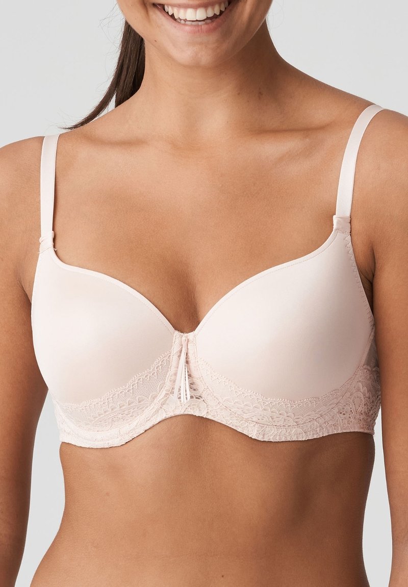 Reggiseno rosa chiaro con coppe lisce, bordi in pizzo e spalline regolabili. Presenta un dettaglio centrale con piccoli fiocchi per un tocco di design aggiuntivo.
