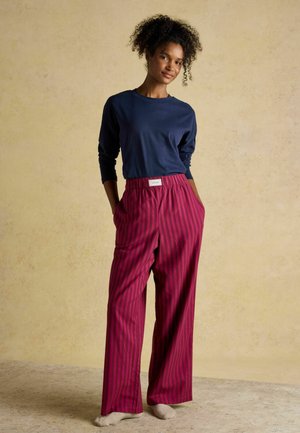 Navy long-sleeve shirt paired with wide-leg, striped burgundy pants. Pants feature an elastic waistband and side pockets. Light-colored background.