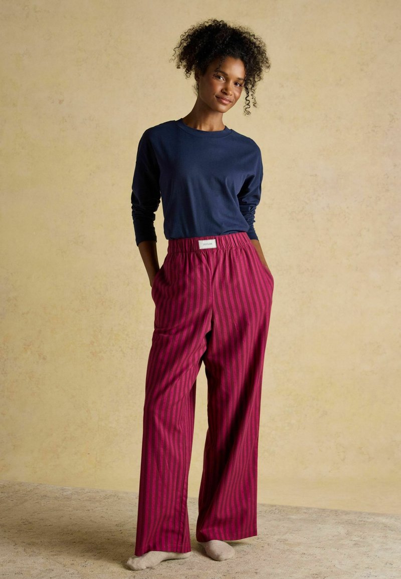 Námornícke tričko s dlhým rukávom v kombinácii s širokými pruhovanými nohavicami v bordovej farbe. Nohavice majú elastický pás a bočné vrecká. Svetlé pozadie.