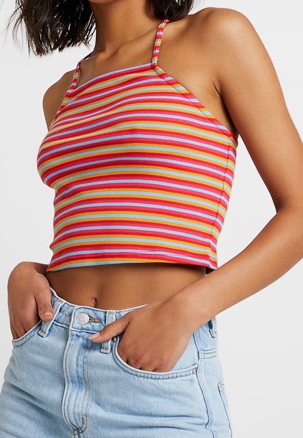Top corto a rayas con finas tirantes en rojo, naranja, amarillo y azul; textura acanalada; combinado con pantalones cortos de mezclilla claros de tiro alto.