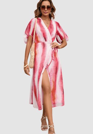 Mujer con vestido cruzado a rayas rosa y blanco con mangas abullonadas, gafas de sol, sandalias con tiras y lleva un bolso de hombro tejido.
