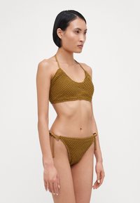 Khaki crochet two-piece bikini; top features a scoop neck and adjustable straps, while the bottom has tie-side closures and a textured finish.