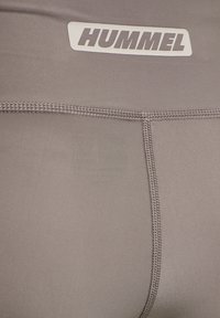 Gray athletic shorts with Hummel logo. Made of smooth, stretchy fabric. Features flatlock seams and a waistband for a streamlined fit.