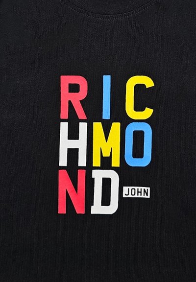 Maglietta nera in tessuto con lettere a blocchi multicolori in grassetto: "RICHMOND" in rosso, blu, giallo e bianco; testo piccolo "JOHN" sotto.