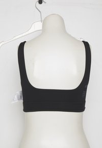 Must spordirinnahoidja valge mannekeeni seljal, riputatud valgele plastikkonksule tavalise valge tausta taustal.