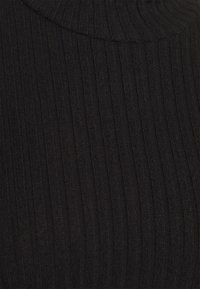 Tecidos em preto com textura canelada e gola alta, apresentando finas linhas verticais e uma textura suave, adequados para uma peça justa.