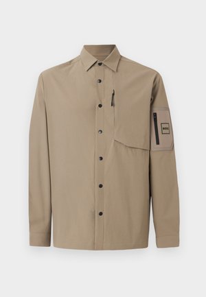 Bež košulja dugih rukava s kragnom, crnim snap gumbima, džepom na prsima sa zatvaračem i džepom s zakrpom sa zatvaračem na lijevom rukavu.