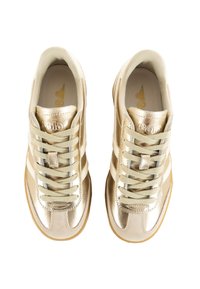 Gula sportskor med en glänsande metallisk yta, utrustade med platta snören och tre vita ränder på varje sida, i kombination med en tan-färgad sula.