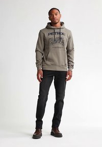 Szürke kapucnis pulóver első oldali motoros grafikával. Fekete farmerral és barna cipővel párosítva. Kenguruzsebbel és húzózsinóros kapucnival.