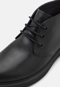 Zapato de cuero negro con cordones, que presenta un acabado suave, punta redonda y cordones tono sobre tono con cuatro ojales; suela de goma mate.