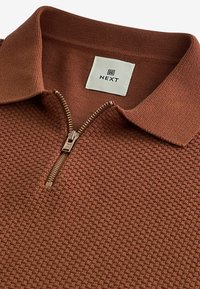 Pull à col zippé marron à texture, avec un col uni et une fermeture éclair bronze ; présente une étiquette carrée NEXT près du col.