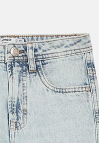 Helehallid teksapüksid, millel on klassikaline viie tasku disain, nööpkinnitus ja kangal tagasihoidlik pleekimise tekstuur.