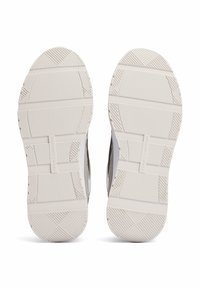 Białe podeszwy sneakerów z teksturowanymi wzorami antypoślizgowymi. Zawierają liniowe rowki i logo marki. Miękki, elastyczny materiał gumowy.