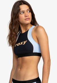 Roxy sportbehå i svart och ljusblå, med en logga i beige, en tajt passform, slät textur och racerback-design med kontrasterande sömmar.