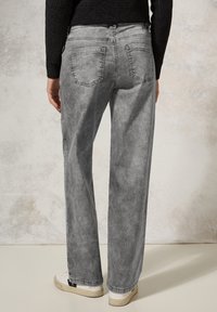 Grijze denim jeans met een ontspannen pasvorm, voorzien van twee achterzakken en subtiele whiskers. Gepaard met witte sneakers.