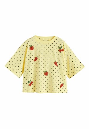 Žltá košeľa s krátkym rukávom s čiernymi bodkami a vyšívanými červenými ovocnými a zeleninovými motívmi rozmiestnenými na prednej strane.