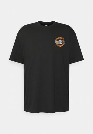 T-shirt noir à manches courtes avec col rond, petit motif sur le côté gauche de la poitrine représentant un cercle de chaîne orange et du texte blanc partiellement visible.