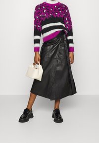 Black leather wrap skirt, fuzzy purple and black patterned sweater, and a small white handbag. Chunky black shoes complete the outfit.