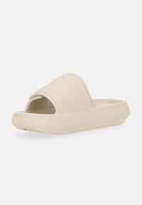 Infradito beige con design aperto davanti, tomaia testurizzata e suola bassa. Presenta un interno liscio e morbido per il massimo comfort.