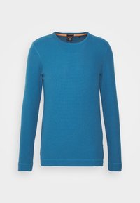 Långärmad tröja med rund hals i mjukt blått tyg, med texturerat stickmönster och kontrasterande orange detalj på den inre halsringen.