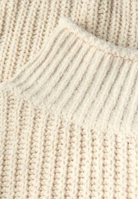 Maglione a maglia color crema con un design testurizzato caratterizzato da coste verticali e un collo morbido e peloso. Il filato spesso conferisce profondità e calore.