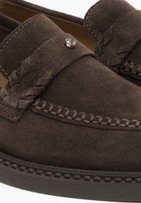 Bruine suède loafers met geweven details, gestikte accenten en een klein metalen embleem op de band. Rondovorm met een dikke zool.
