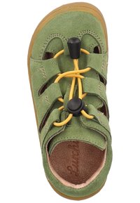 Vihreät mokkanahkakengät, joissa on keltaiset joustavat nauhat ja musta solki. Varusteena joustava kumipohja ja leikattu muotoilu hengittävyyttä varten.