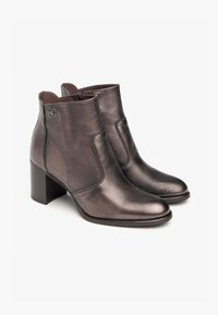 Bottes en cuir brun foncé à hauteur de cheville avec un bout carré et un talon bloc. Présente des coutures sur les côtés et un logo subtil sur le côté extérieur.