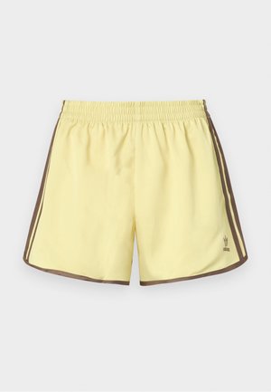 Geltoni sportiniai šortai su rudos spalvos šoninėmis juostelėmis. Yra elastingas juosmuo ir Adidas logotipas apatiniame kairiame kampe. Lygus poliesterio audinys.