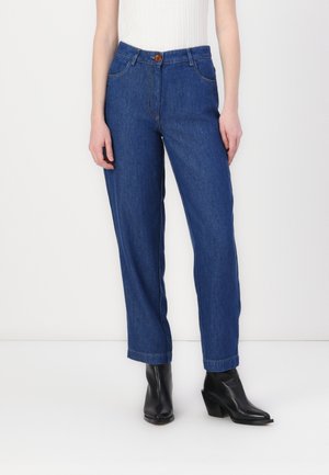 Blue denim jeans with a straight cut, featuring a button closure, front pockets, and prominent stitching. Worn with black ankle booties.