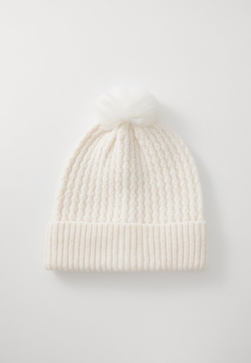 Gorro de punto en suave material blanco, con un puño acanalado y un pompón esponjoso en la parte superior, creando una apariencia texturizada y con capas.