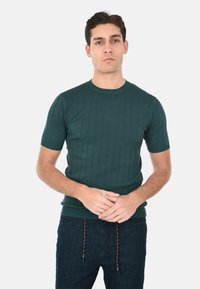 Maglione verde a maniche corte in maglia, caratterizzato da costine verticali e colletto tondo. Texture morbida con un design aderente.