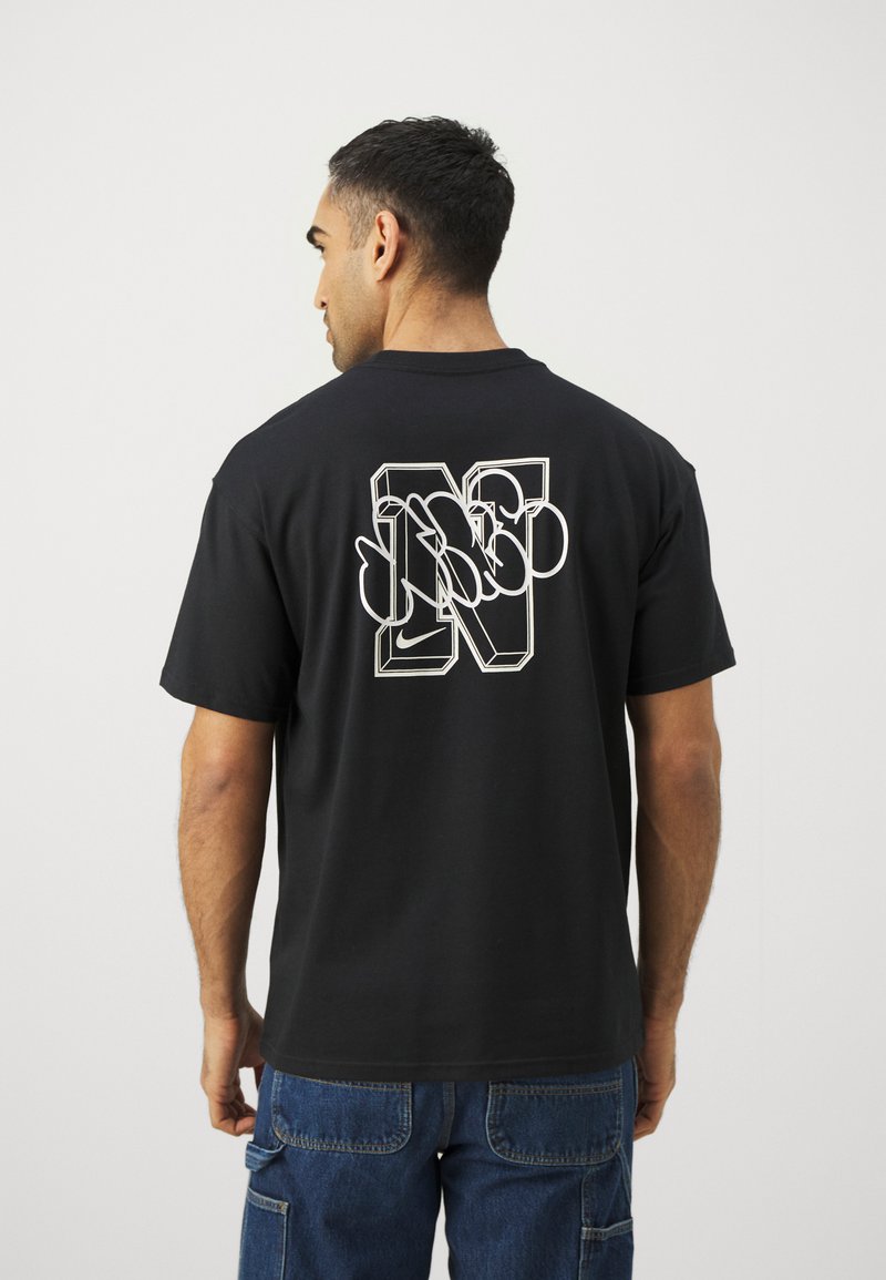 Schwarzes Baumwoll-T-Shirt mit einem großen, weißen, umrandeten grafischen Design des Buchstabens "N" auf dem Rücken. Kurze Ärmel, klassischer Schnitt.