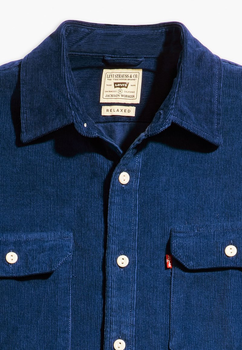Niebieska koszula z korduroju z rozpostartym kołnierzem, zapinana na guziki, z dwoma kieszeniami na piersi; posiada metkę z napisem "Levi Strauss & Co." oraz "Relaxed."
