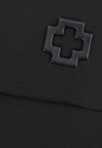 Schwarze Stofftasche mit einem erhabenen schwarzen Kreuzemblem. Das Material ist strukturiert mit genähten Details. Kompakte, rechteckige Form.