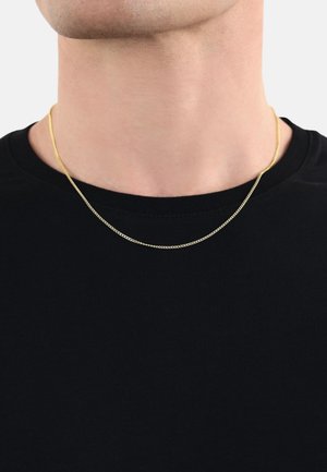 Collana a catena color oro appoggiata su una maglietta nera, caratterizzata da un design delicato e sottile con una texture liscia e una leggera lucentezza.