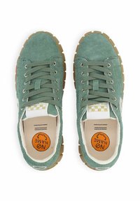 Sneakers in suede verde con suola in gomma, punta tonda e occhielli in metallo. Presentano una soletta imbottita con un logo arancione e un'etichetta a scacchi.