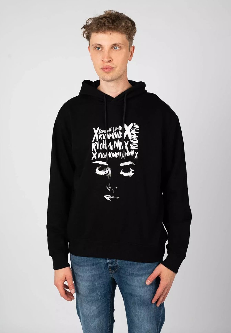 Felpa nera in cotone, con una stampa grafica di un volto in testo bianco e elementi di design sulla parte anteriore. Vestibilità regolare con cappuccio.