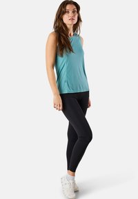 Haut de sport sans manches bleu clair associé à un legging noir et des baskets blanches ; présente un tissu lisse et une coupe ajustée.