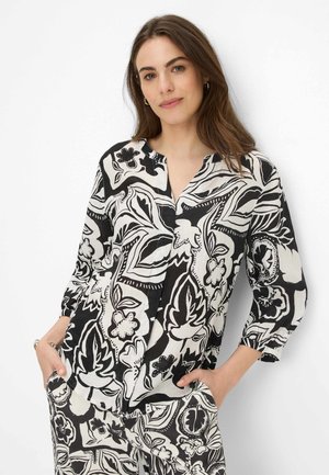 Blusa a fiori in bianco e nero con maniche a tre quarti e scollatura a V profonda, realizzata in tessuto leggero. Presenta una vestibilità morbida.