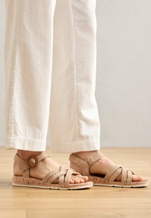 Sandalias beige de tiras fabricadas en suave ante con suela de corcho. Presentan un detalle decorativo de botón y un diseño de punta abierta.