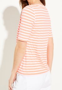 Camiseta de algodón de manga corta, con rayas horizontales coral y blancas, un escote redondo y un corte relajado.