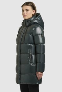 Polstret parka i mørkegrøn med blank finish, der har hætte, sidelommer og et karakteristisk horisontalt quiltet mønster.
