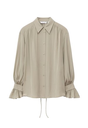 Beige bluse med lange ærmer, knapper foran, spids krave, rynkede skuldre og flæsekantede manchetter med snørejustering nederst.