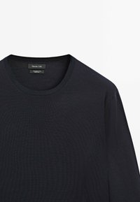 Maglione in lana blu navy con scollatura rotonda, bordi a coste e texture liscia. L'etichetta riporta "Massimo Dutti", che indica il marchio e il materiale.